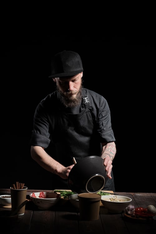 Chef gently stirring homemade risotto cooking in a wide pan